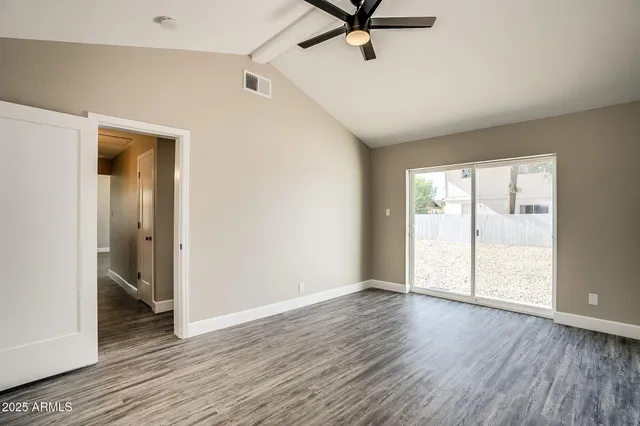 an empty room with wooden floor cabinet and windows