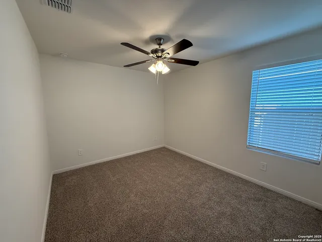 an empty room with a window and a fan