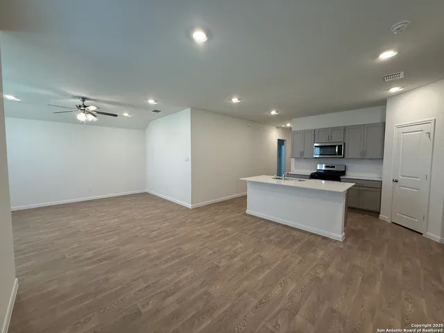 a view of kitchen with kitchen island stainless steel appliances a sink and cabinets