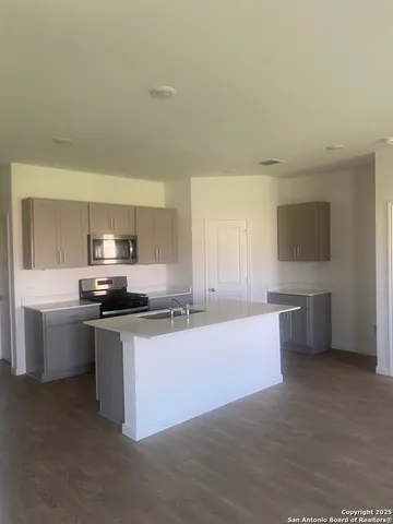 a kitchen with stainless steel appliances a sink a stove top oven a counter space and cabinets