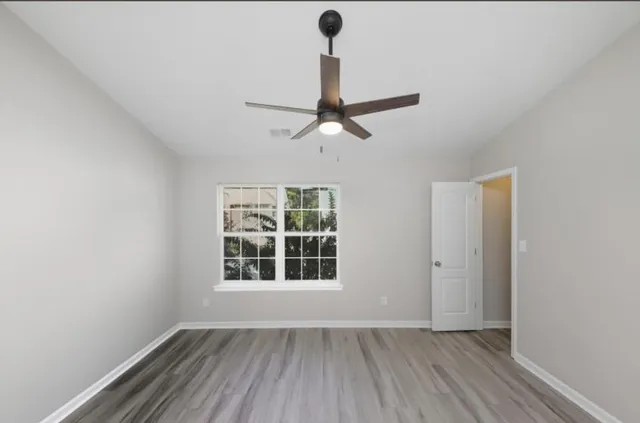 an empty room with a window and ceiling fan