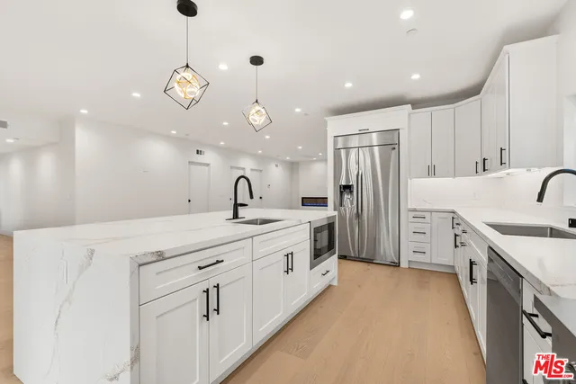 a large white kitchen with a sink and dishwasher