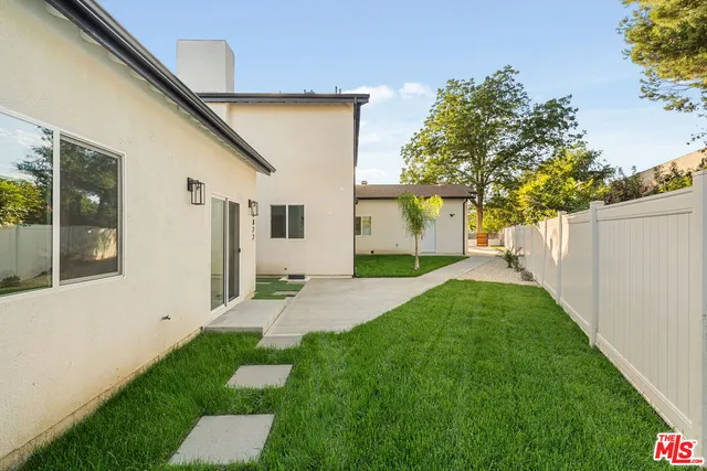a view of an empty room with wooden floor and a kitchen