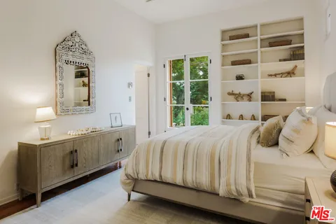 a bedroom with a bed a couch and large window