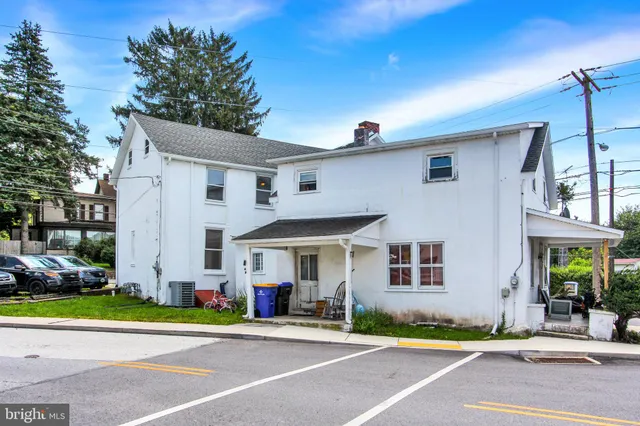 a front view of a house with a garden and trees