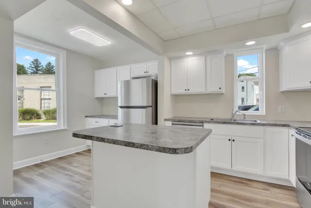 a kitchen with kitchen island granite countertop a sink cabinets and refrigerator