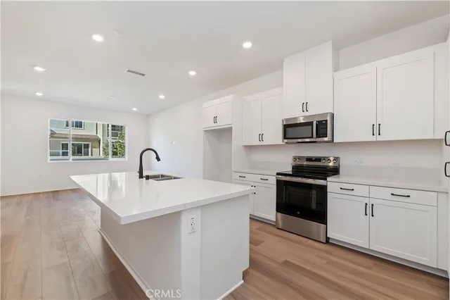 a kitchen with stainless steel appliances granite countertop a sink stove top oven and cabinets