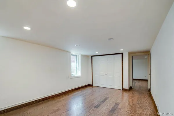 a view of an empty room with wooden floor and closet