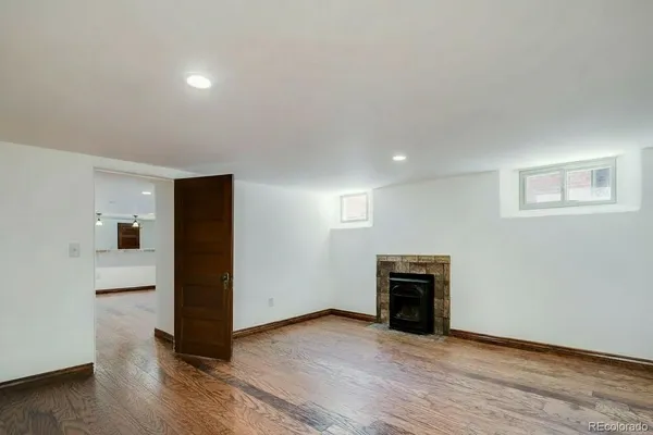 an empty room with wooden floor fireplace and windows