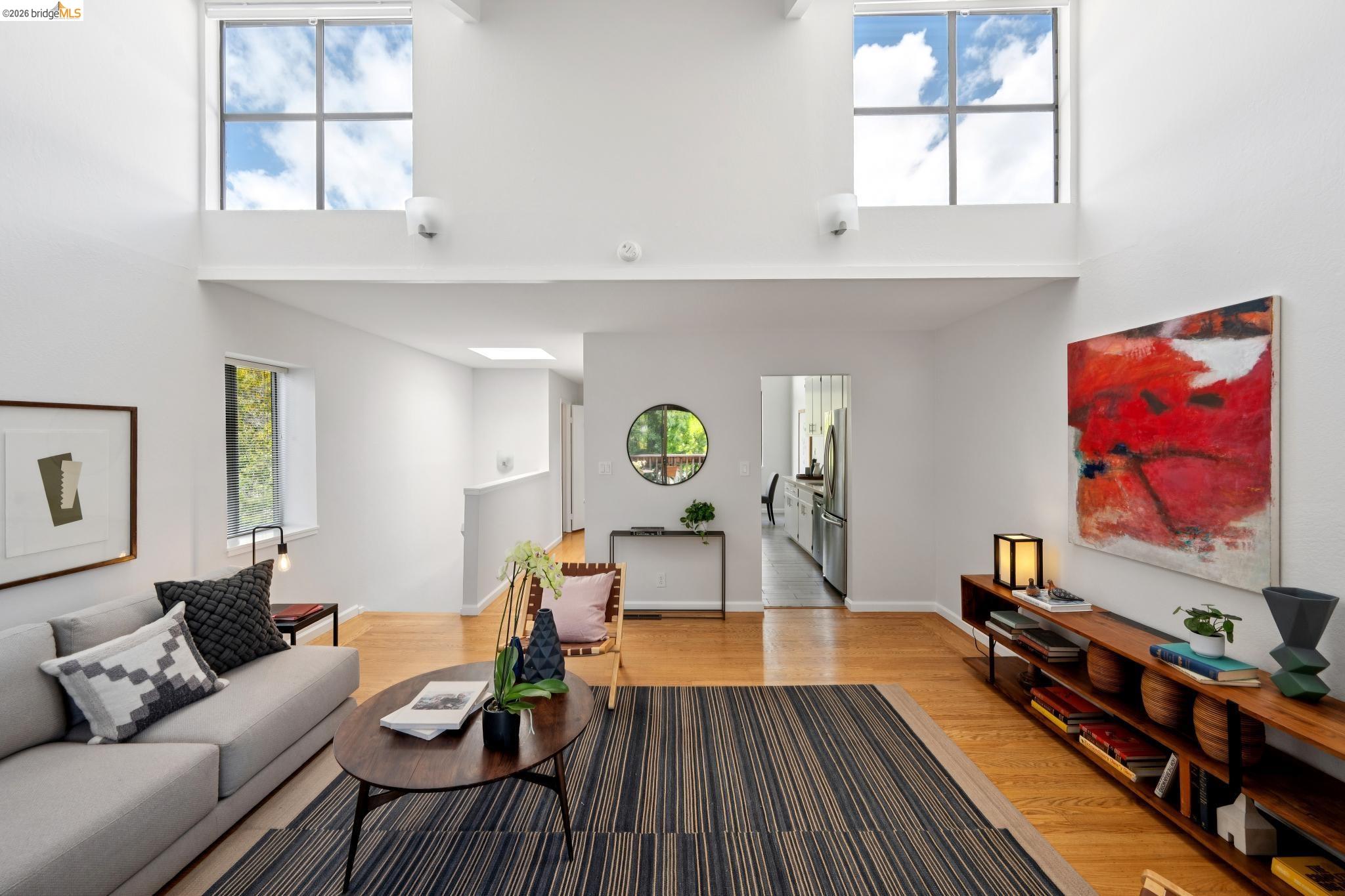 1340 Henry Street Berkeley, CA 94709 - Photo 10 of 52 Living area featuring high vaulted ceilings with transom windows, wood-finish flooring, and a built-in shelving unit
