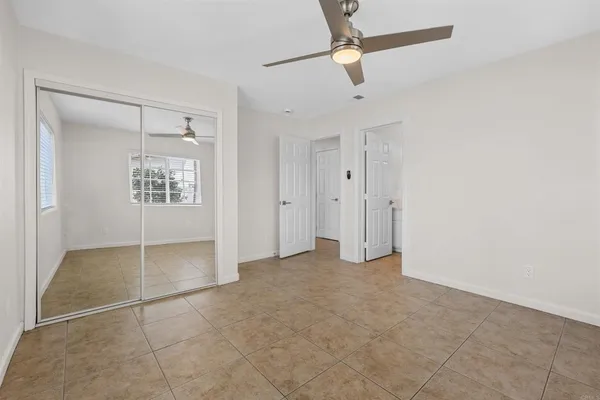 an empty room with windows and fan