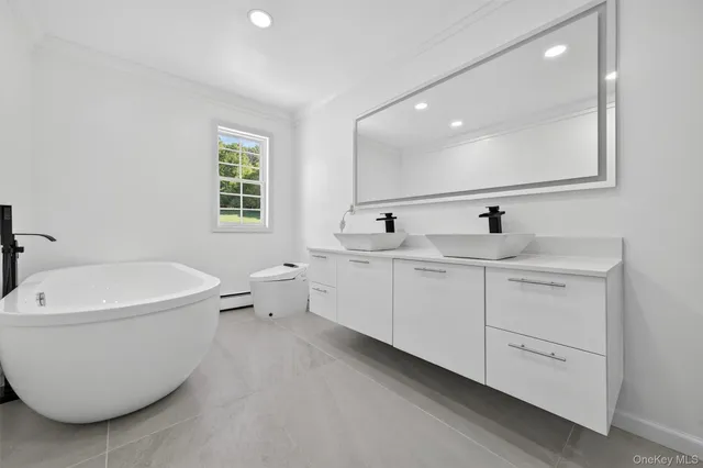 a spacious bathroom with a double vanity sink a mirror and a bathtub