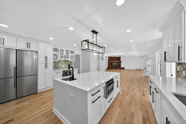 a kitchen with kitchen island a counter top space stainless steel appliances and wooden floor