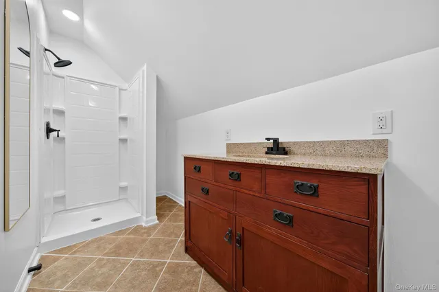 a bathroom with a granite countertop sink a mirror and shower