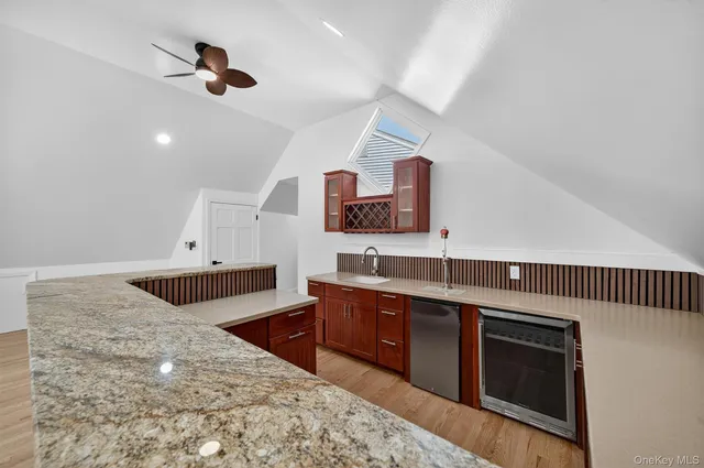 a living room with stainless steel appliances kitchen island granite countertop a sink and wooden cabinets
