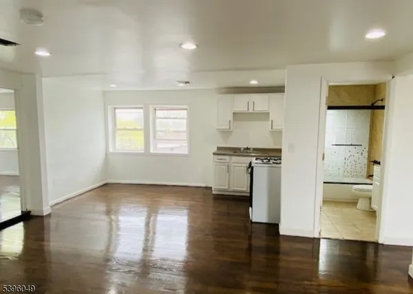 an empty room with wooden floor and a kitchen