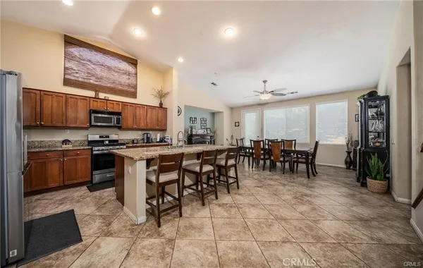 a kitchen with stainless steel appliances granite countertop a stove a sink dishwasher a refrigerator with a dining table and chairs