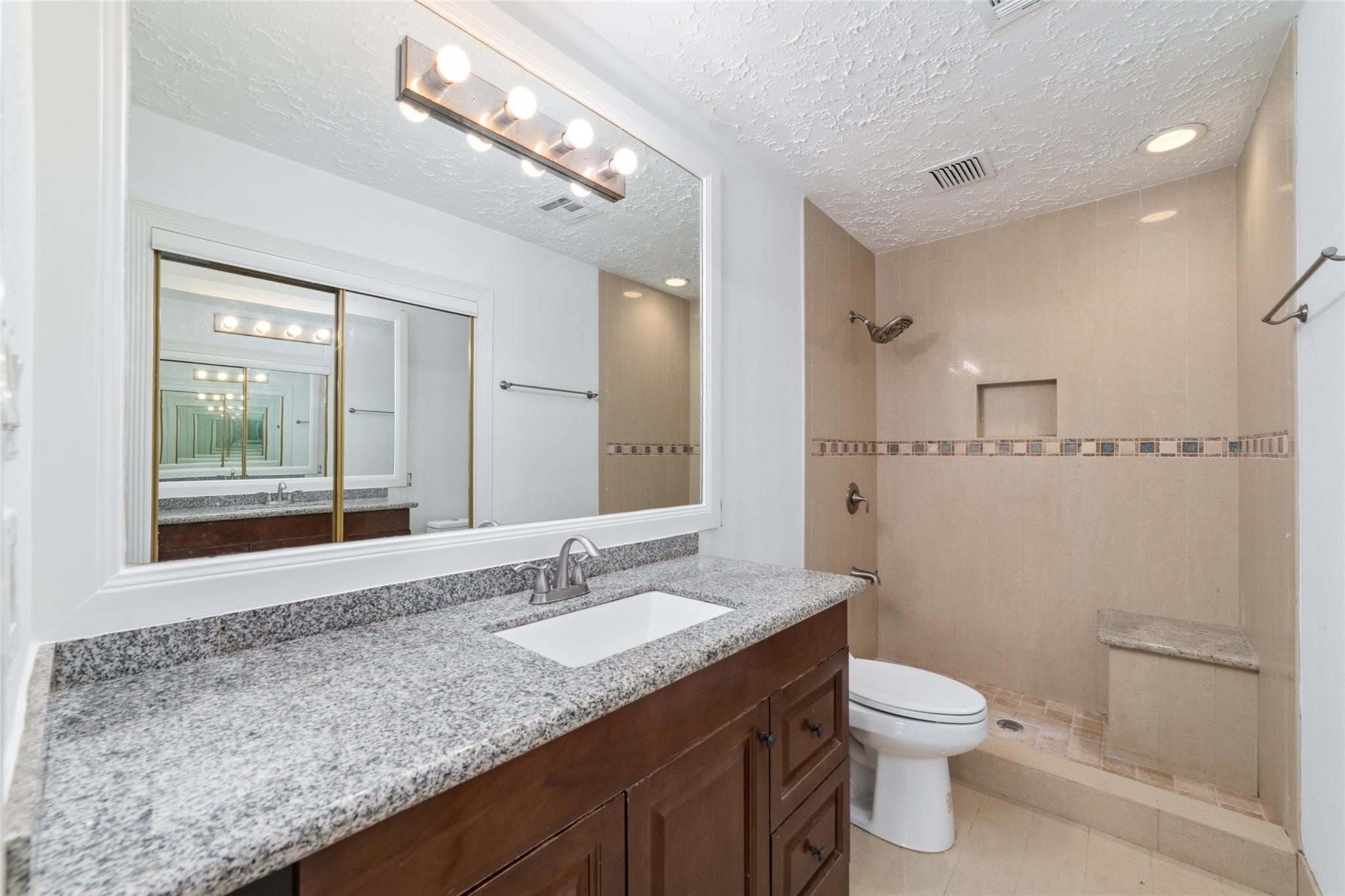 16123 Ridgegreen Drive Houston, TX 77082 - Photo 13 of 21 a bathroom with a granite countertop sink a toilet and a mirror