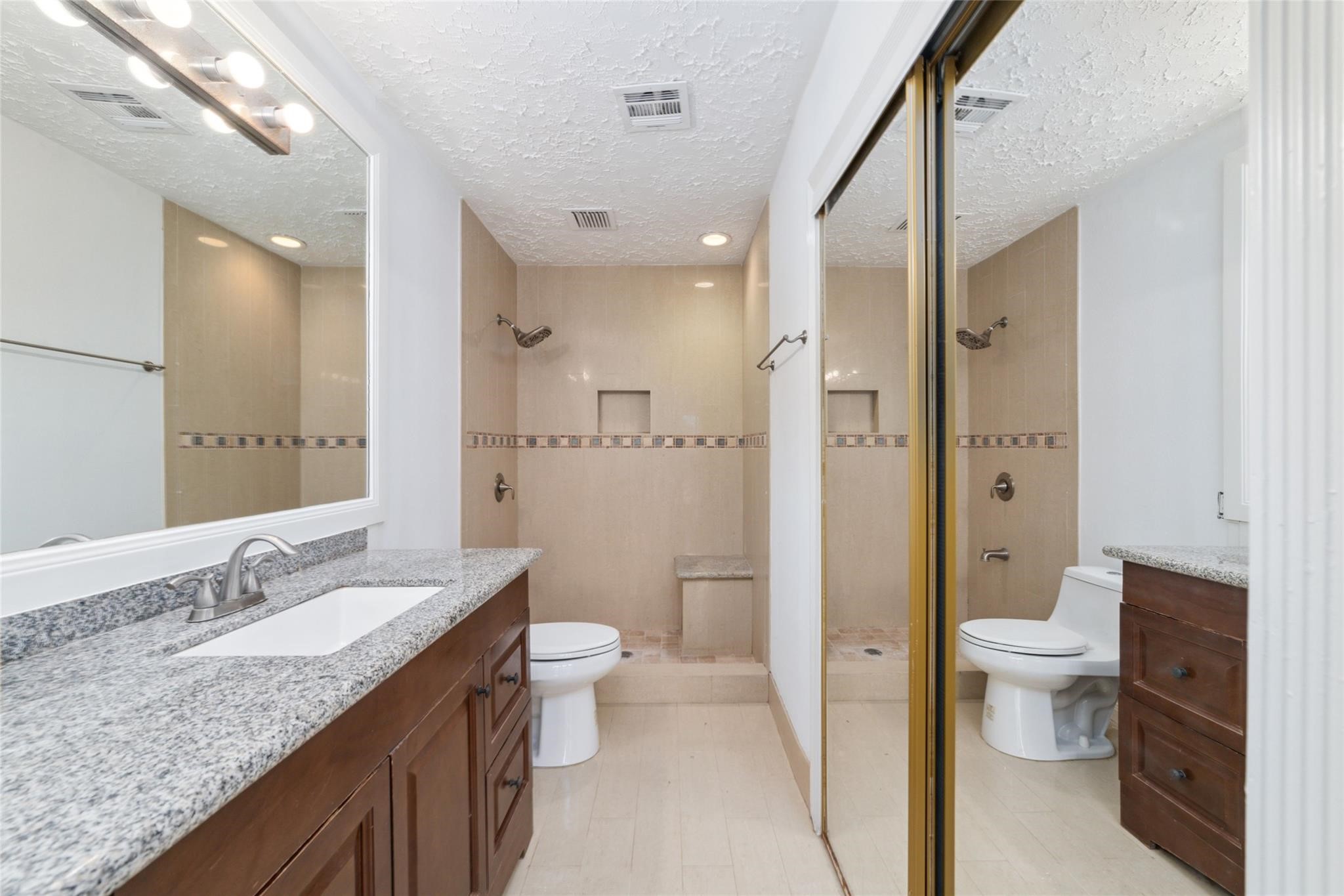 16123 Ridgegreen Drive Houston, TX 77082 - Photo 14 of 21 a bathroom with a granite countertop sink a toilet a shower and a mirror