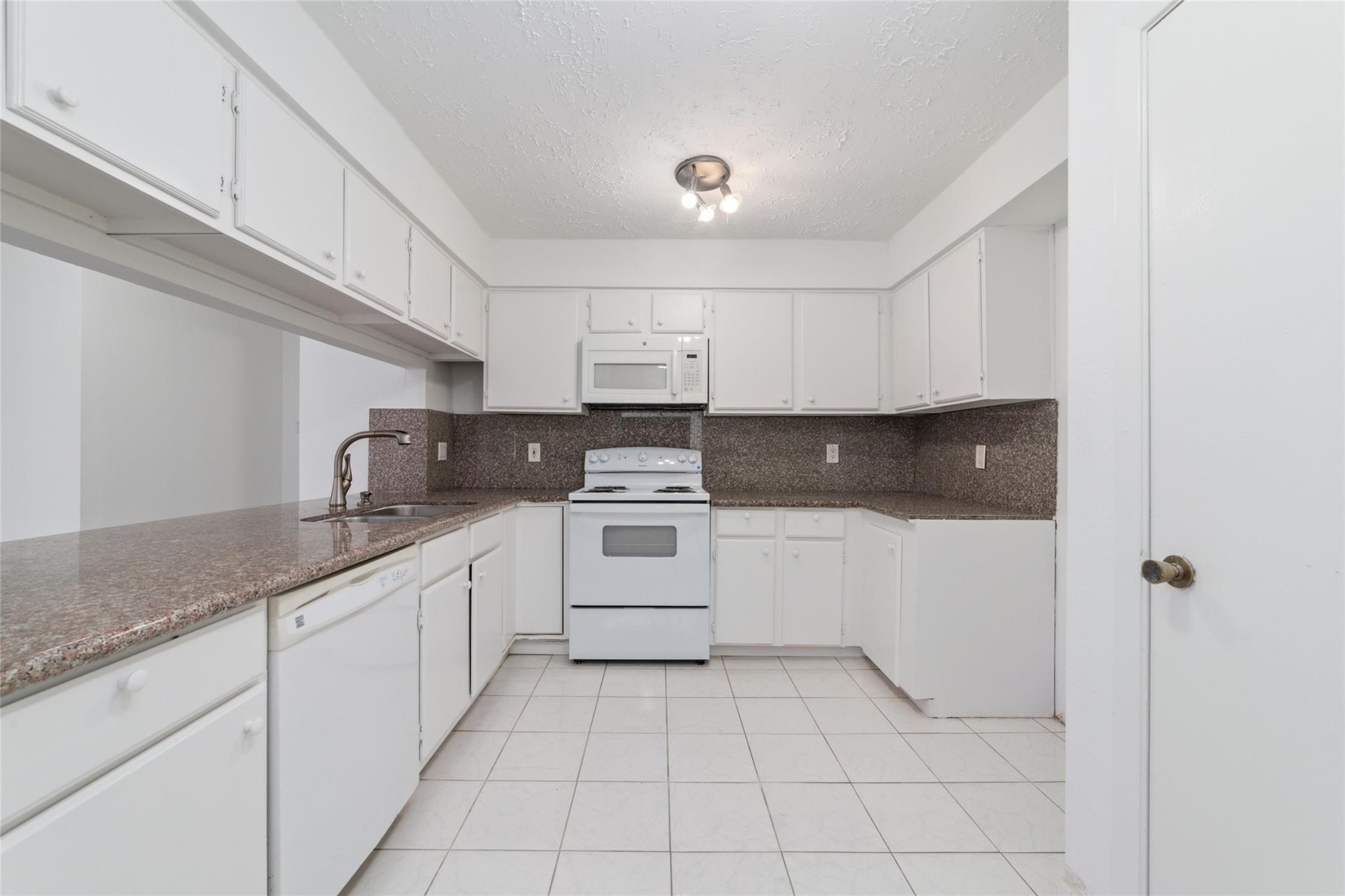 16123 Ridgegreen Drive Houston, TX 77082 - Photo 8 of 21 a kitchen with granite countertop white cabinets and white appliances
