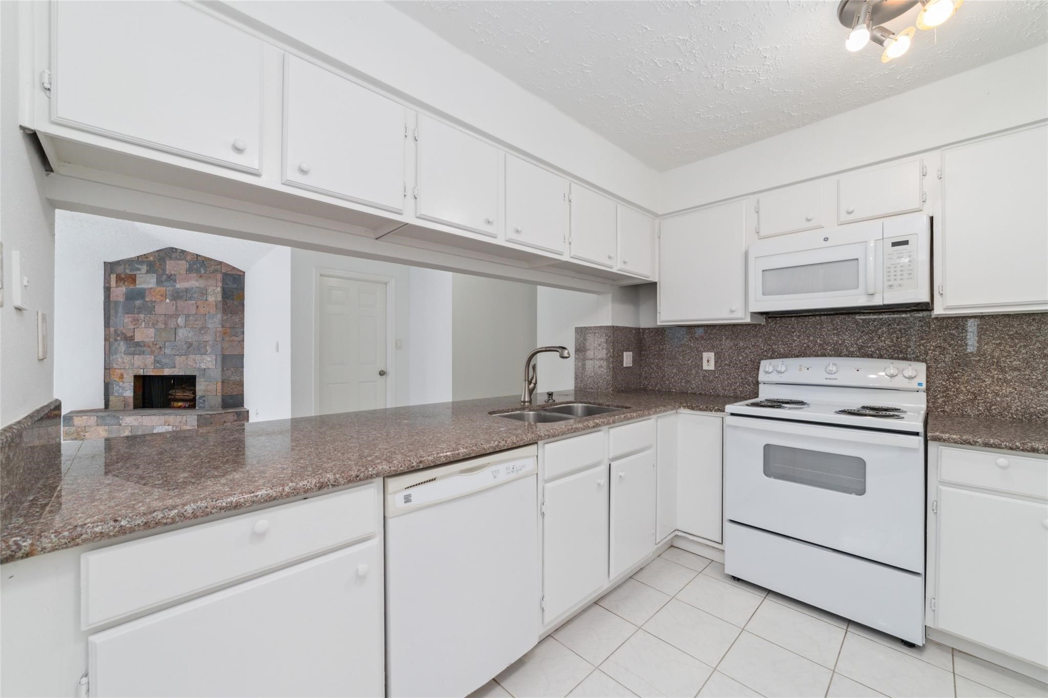 16123 Ridgegreen Drive Houston, TX 77082 - Photo 9 of 21 a kitchen with granite countertop white cabinets and white appliances