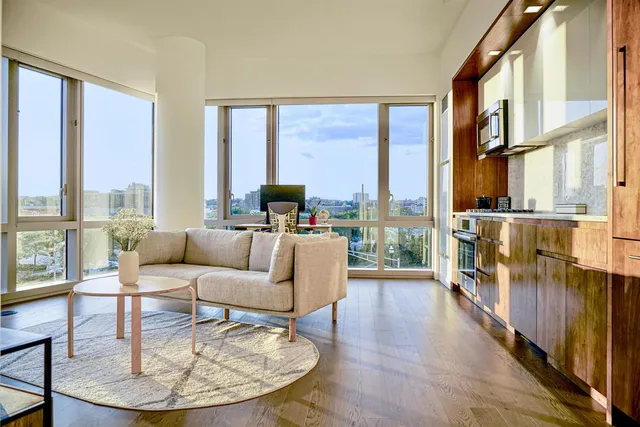 a living room with furniture large windows a rug and a floor to ceiling window