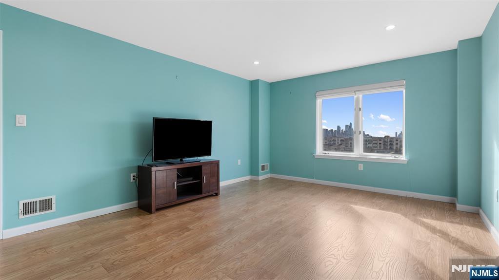605 Thornton Court, Unit T605 Edgewater, NJ 07020 - Photo 17 of 34 en empty room with window and flat screen tv