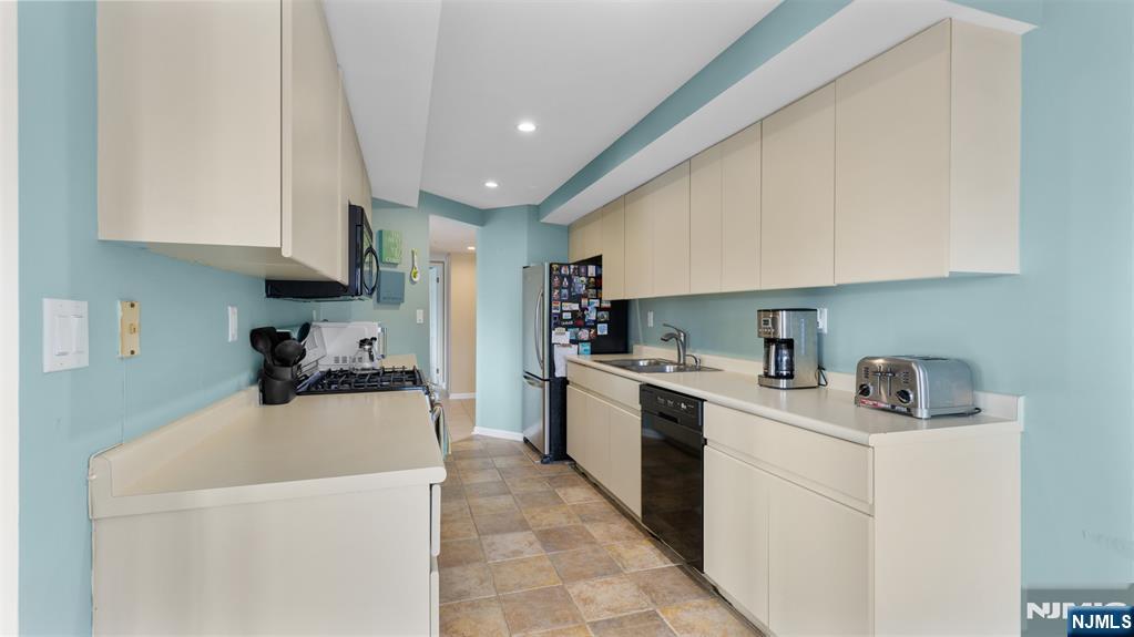 605 Thornton Court, Unit T605 Edgewater, NJ 07020 - Photo 9 of 34 a kitchen with a sink a stove top oven and white cabinets