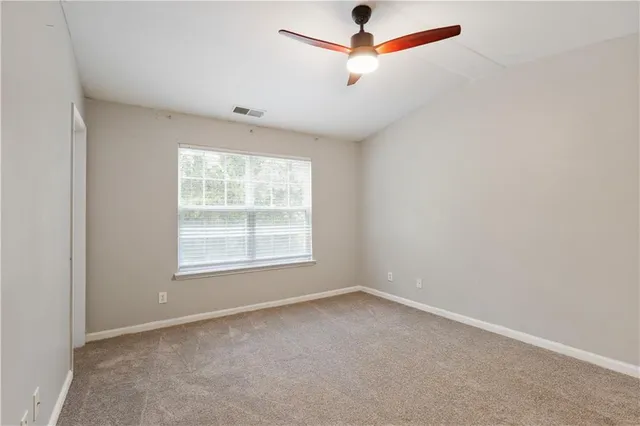 an empty room with a window and a fan