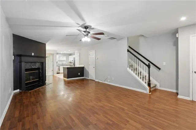 a view of an empty room with wooden floor and a fireplace