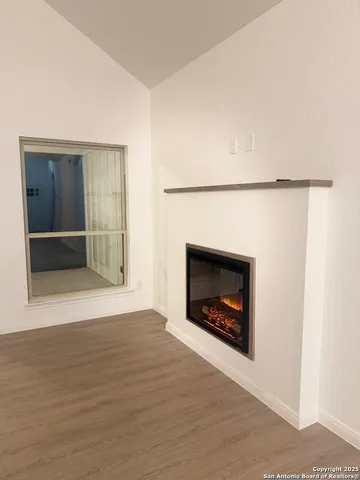 a view of an empty room with wooden floor and a fireplace