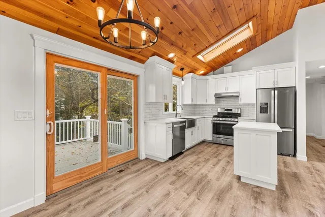 a kitchen with a refrigerator a stove top oven a sink and dishwasher with wooden floor