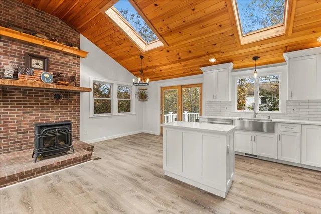 a kitchen with granite countertop a stove a sink and white cabinets with wooden floor