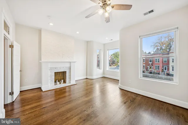 an empty room with wooden floor chandelier fan and windows