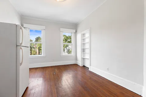 an empty room with wooden floor and windows