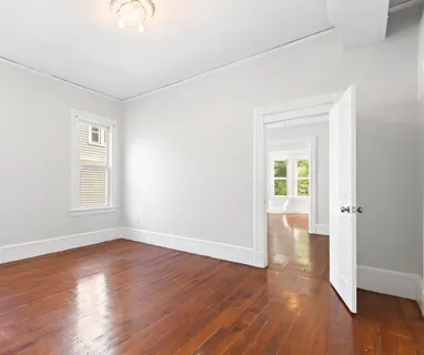 an empty room with wooden floor and windows