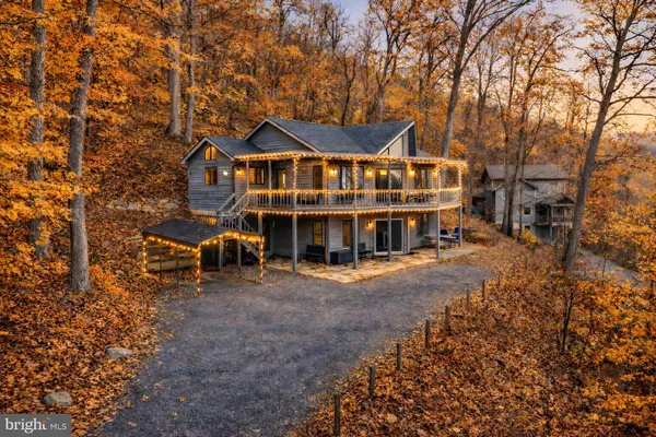 a view of a big house with a large tree and lawn chairs under an umbrella