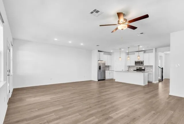 a view of a kitchen with kitchen island wooden floor and stainless steel appliances
