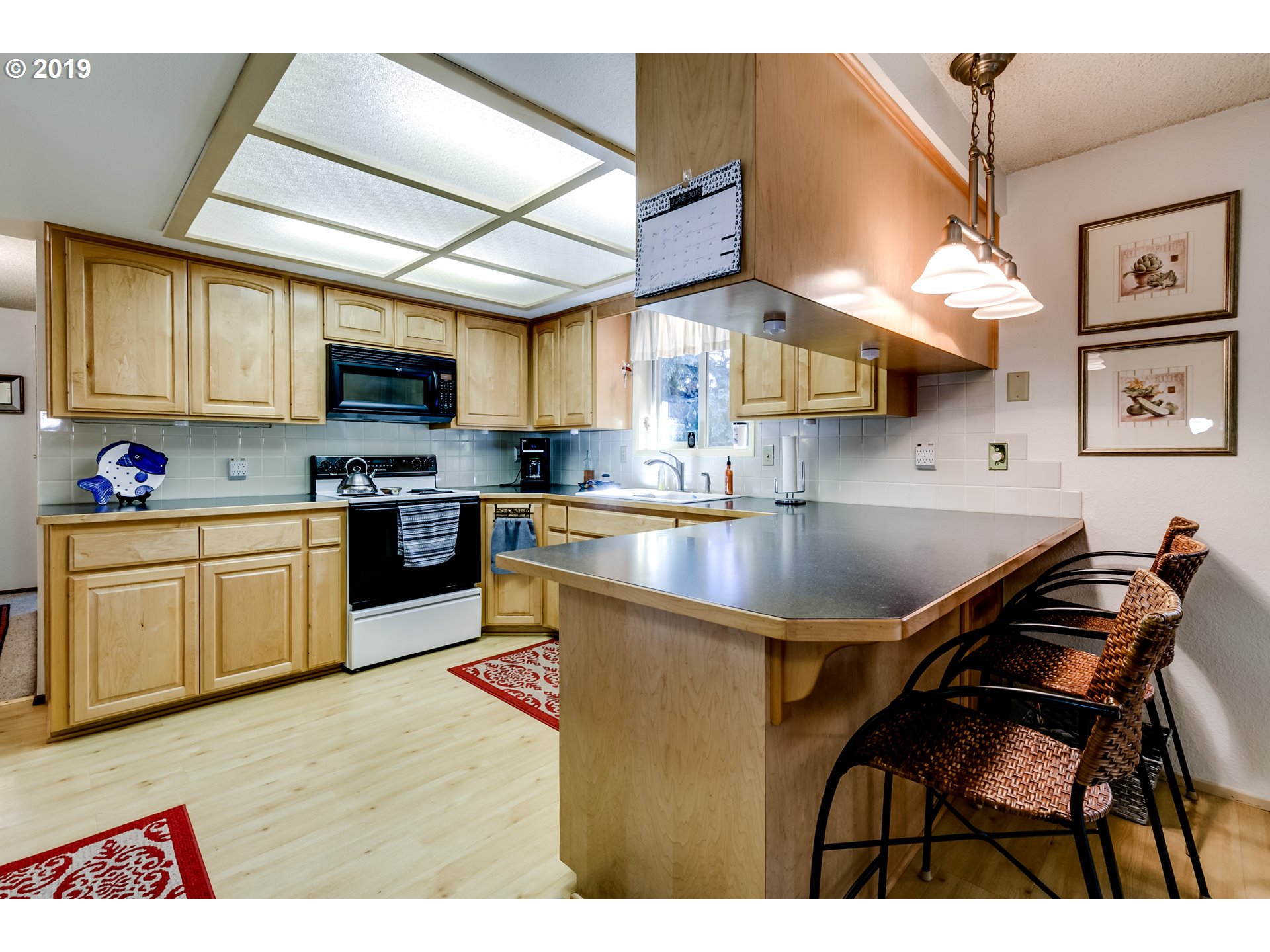 537 66th Street Springfield, OR 97478 - Photo 20 of 32 a kitchen with stainless steel appliances granite countertop a sink dishwasher a stove a refrigerator a microwave oven with cabinets and wooden floor