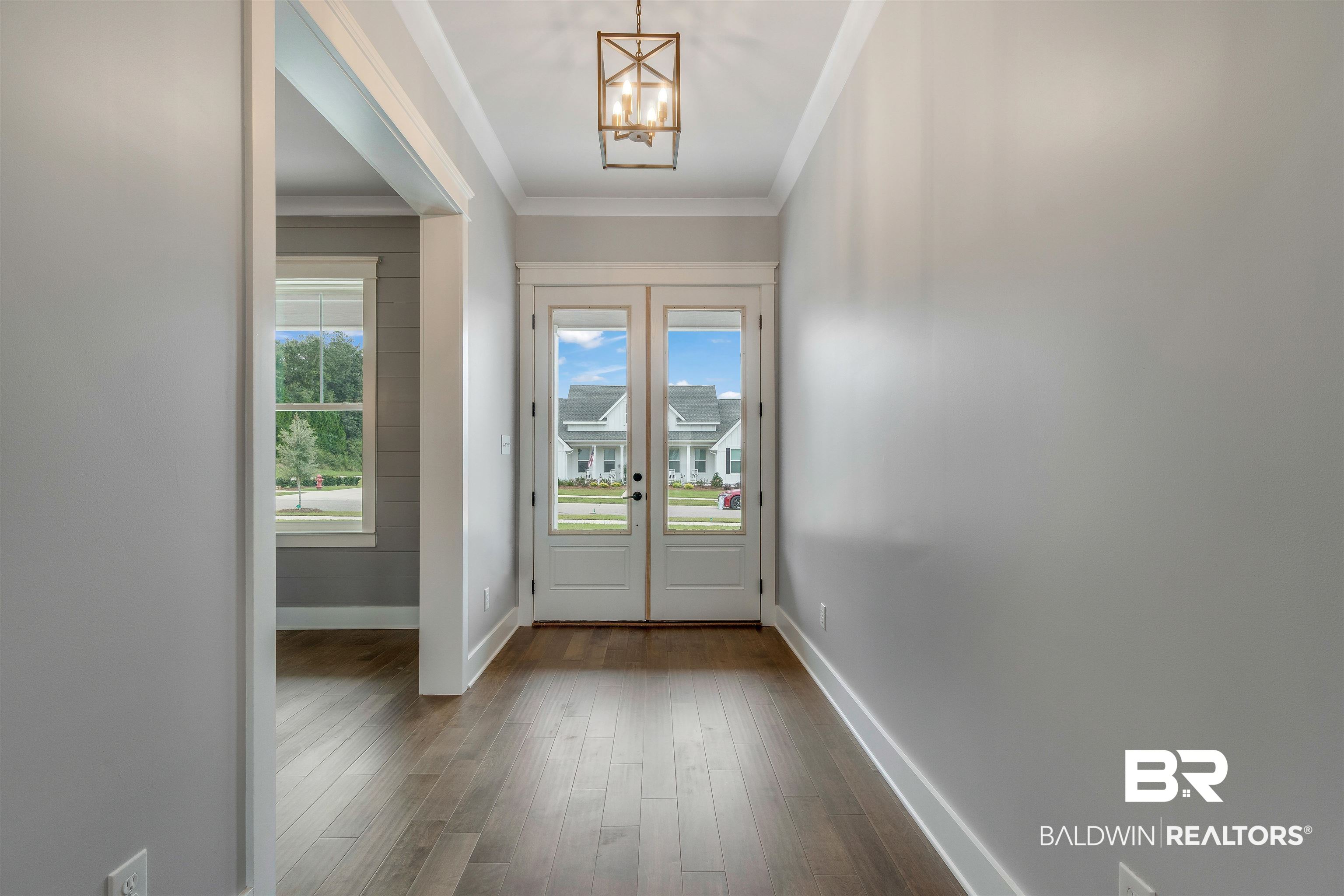 10985 Atrium Avenue Fairhope, AL 36532 - Photo 15 of 58 Entryway with crown molding, wood finished floors, a chandelier, and french doors
