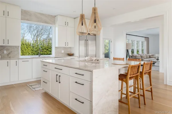 a kitchen with stainless steel appliances kitchen island granite countertop a stove a sink and white cabinets with wooden floor