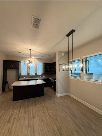a large white kitchen with a large island wooden floor and stainless steel appliances