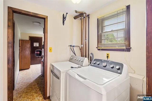 a view of washer and dryer with bathroom in the background