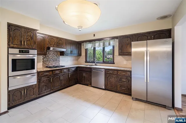 a kitchen with stainless steel appliances granite countertop a refrigerator and a stove top oven