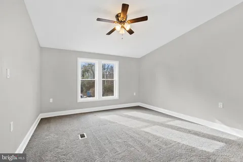 an empty room with a window and a fan