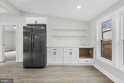a view of an empty room with wooden floor and a bathroom