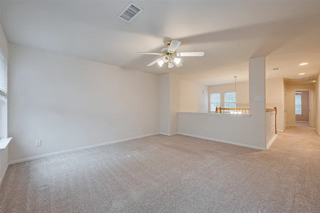 an empty room with a kitchen and a ceiling fan