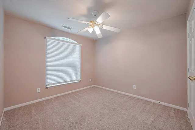 an empty room with chandelier fan and windows