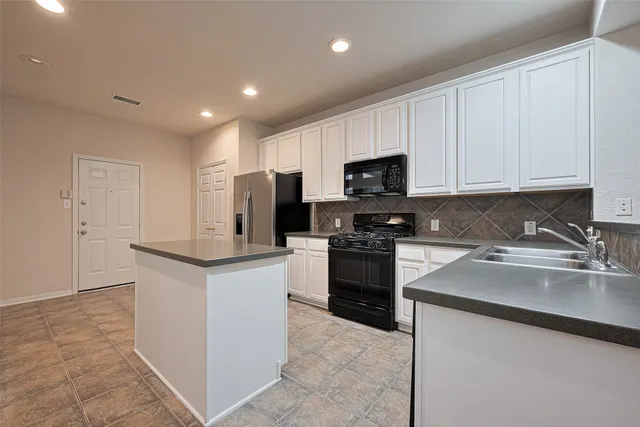 a kitchen with granite countertop white cabinets and stainless steel appliances