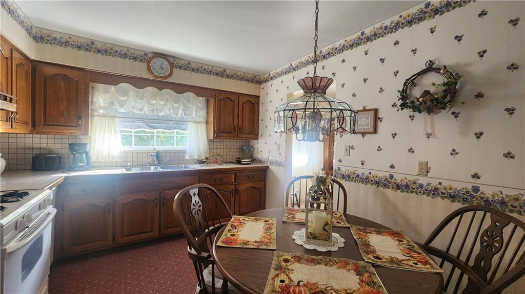 525 Burns Street Vandergrift, PA 15690 - Photo 9 of 25 a kitchen with granite countertop a stove a sink dishwasher a dining table and chair with wooden floor